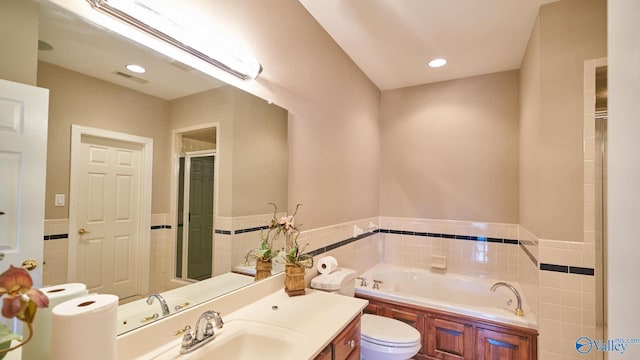 full bath featuring tile walls, a garden tub, toilet, and a wainscoted wall