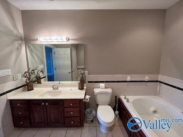 bathroom with vanity, tile patterned floors, tile walls, a tub to relax in, and toilet