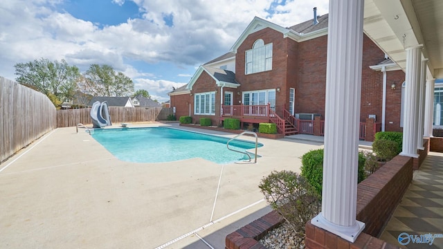 view of swimming pool featuring a fenced in pool, a fenced backyard, a water slide, a wooden deck, and a patio area