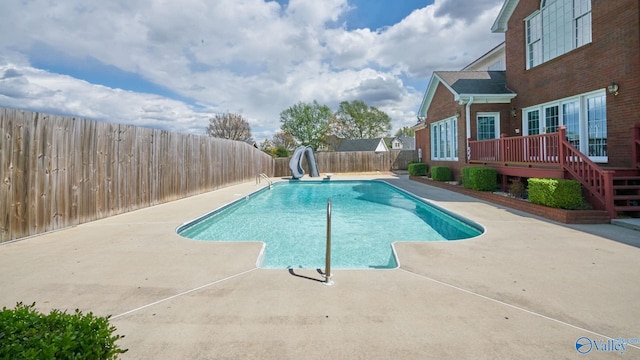 view of swimming pool featuring a water slide, a fenced in pool, a fenced backyard, a patio, and a deck