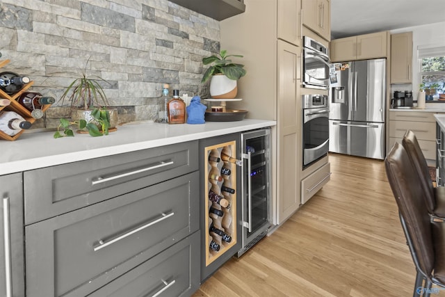 kitchen with wine cooler, decorative backsplash, gray cabinets, light wood-type flooring, and stainless steel appliances