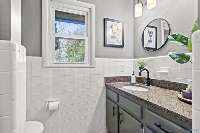 bathroom with vanity, toilet, and tile walls