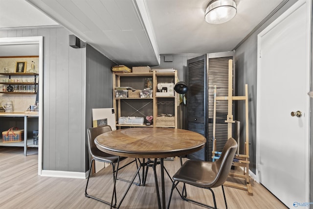 dining room with light hardwood / wood-style floors and wood walls