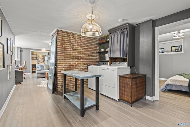 laundry area featuring ornamental molding, brick wall, separate washer and dryer, built in features, and light hardwood / wood-style flooring