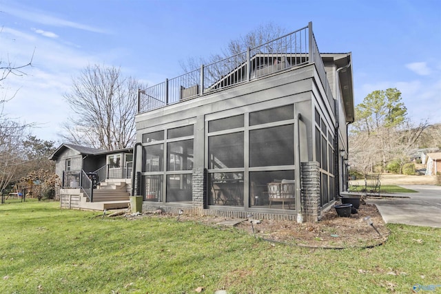 rear view of house with a yard and a sunroom