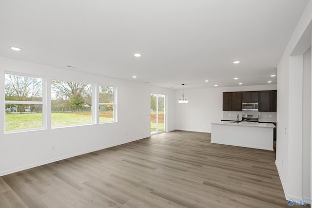 unfurnished living room with sink, hardwood / wood-style flooring, and a chandelier