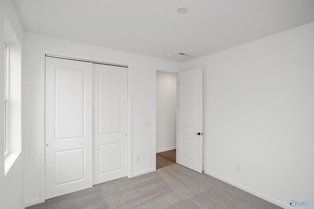 unfurnished bedroom featuring light colored carpet and a closet