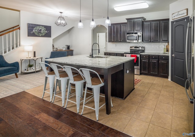 kitchen featuring tasteful backsplash, a kitchen breakfast bar, a kitchen island with sink, stainless steel appliances, and a sink