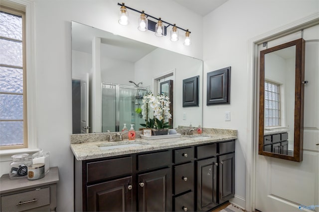 full bath with a sink, a shower stall, and double vanity