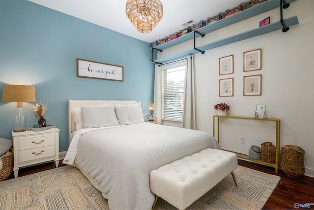 bedroom with baseboards, visible vents, an inviting chandelier, and wood finished floors