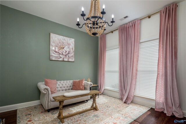 living area with a healthy amount of sunlight, wood-type flooring, and a chandelier