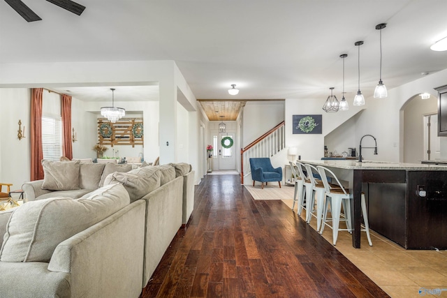 living room featuring arched walkways, dark wood-style flooring, and stairs