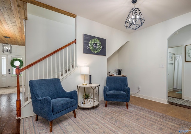 sitting room featuring arched walkways, wood finished floors, stairs, and an inviting chandelier