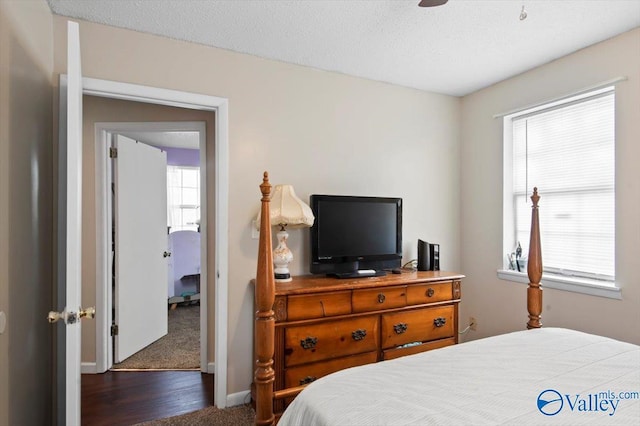 bedroom with ceiling fan, dark carpet, and a textured ceiling