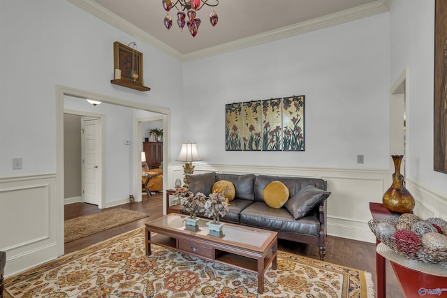 living room with hardwood / wood-style floors, a high ceiling, a chandelier, and crown molding