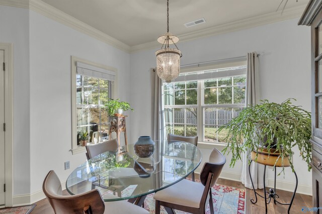 dining space with hardwood / wood-style flooring, a healthy amount of sunlight, and crown molding