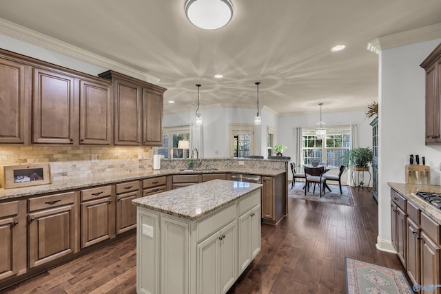 kitchen with hanging light fixtures, dark wood-type flooring, a center island, and crown molding