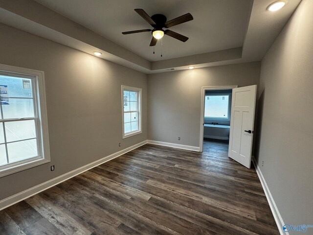 spare room featuring ceiling fan, a tray ceiling, and dark wood-type flooring