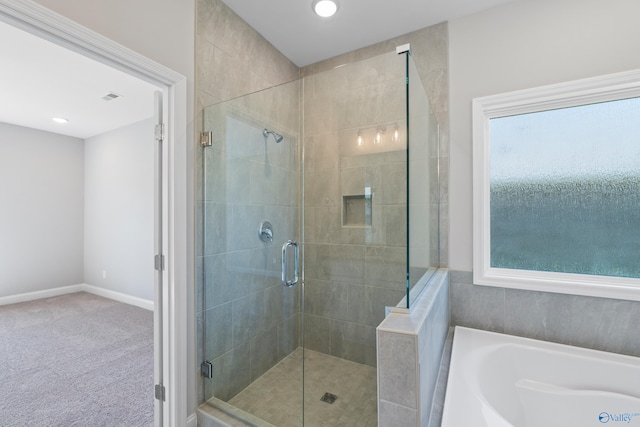 bathroom with shower with separate bathtub and a wealth of natural light