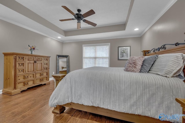 bedroom featuring recessed lighting, light wood-style flooring, a tray ceiling, and baseboards