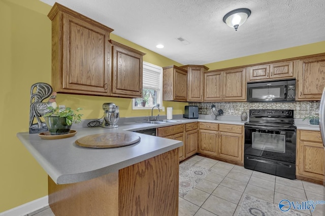 kitchen with a peninsula, black appliances, visible vents, decorative backsplash, and a sink