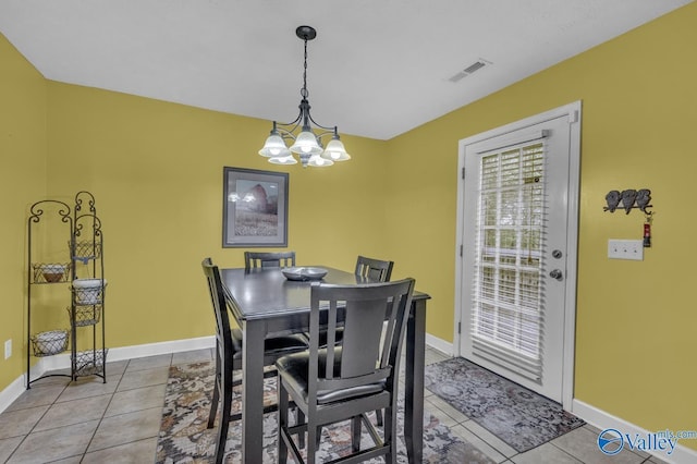 tiled dining room with a chandelier, baseboards, and visible vents