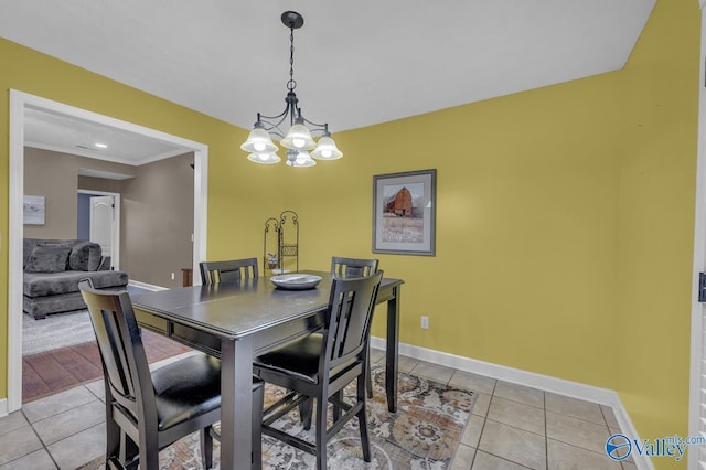 dining area featuring a notable chandelier, baseboards, crown molding, and light tile patterned flooring