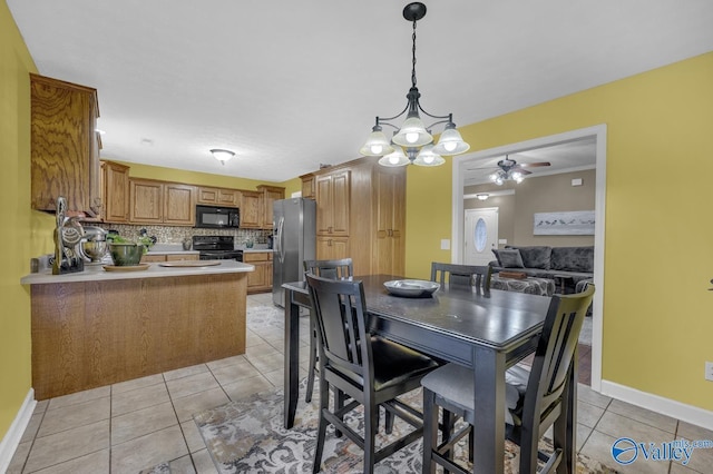 dining room featuring ceiling fan with notable chandelier, light tile patterned floors, and baseboards