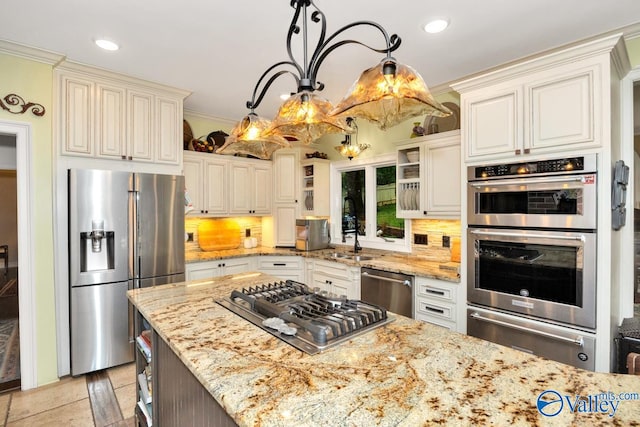 kitchen with light stone counters, hanging light fixtures, backsplash, appliances with stainless steel finishes, and ornamental molding