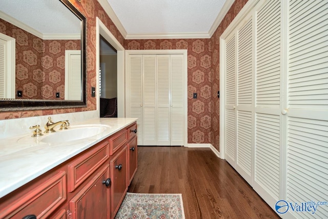 bathroom featuring a textured ceiling, hardwood / wood-style flooring, vanity, and crown molding