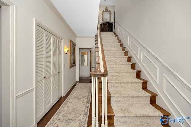 stairway with ornamental molding and wood-type flooring