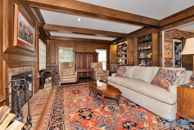 living room with a brick fireplace, a textured ceiling, wood walls, and beam ceiling