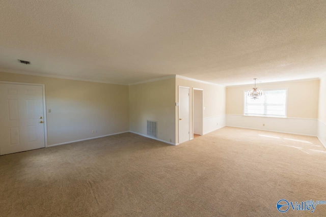 unfurnished room featuring a textured ceiling, ornamental molding, an inviting chandelier, and carpet floors