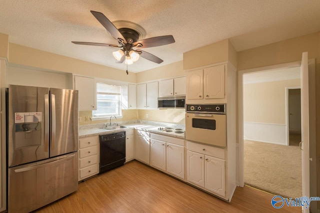 kitchen featuring stainless steel appliances, sink, white cabinetry, a textured ceiling, and light hardwood / wood-style floors