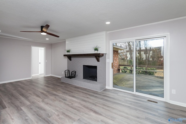 unfurnished living room with crown molding, a textured ceiling, a fireplace, and light wood-type flooring