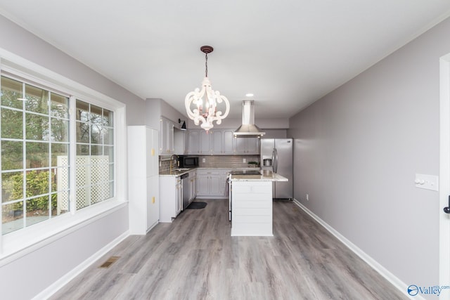 kitchen with appliances with stainless steel finishes, backsplash, a center island, decorative light fixtures, and a chandelier