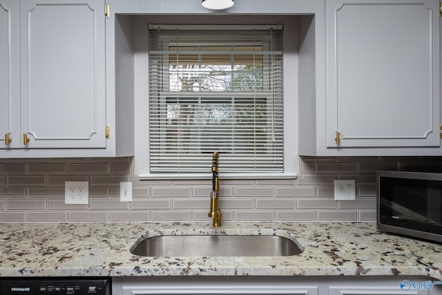 kitchen featuring tasteful backsplash, dishwashing machine, sink, and white cabinets