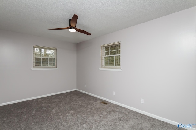 empty room with ceiling fan, dark carpet, and a textured ceiling