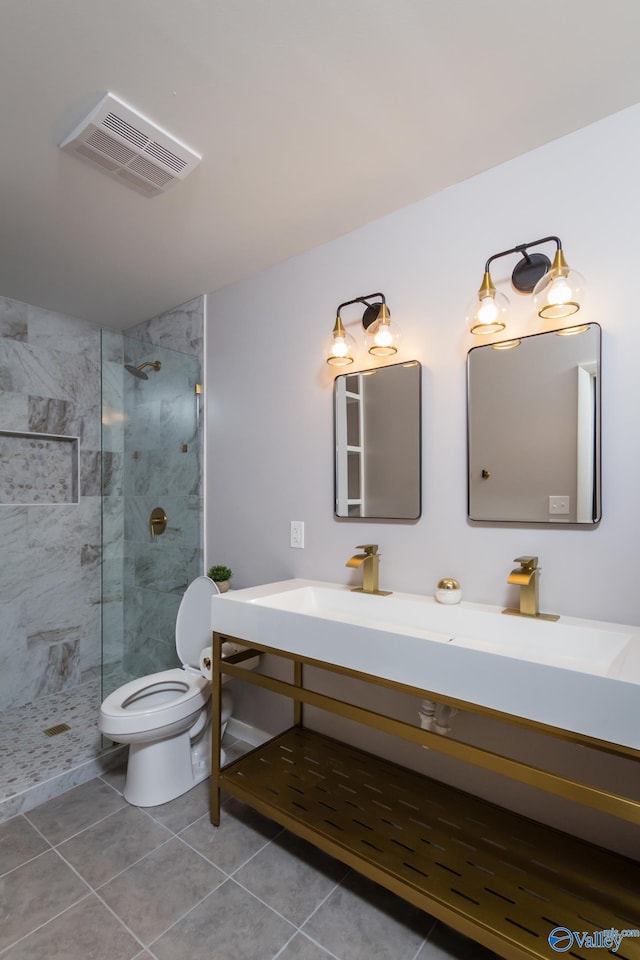 bathroom with tiled shower, vanity, toilet, and tile patterned flooring