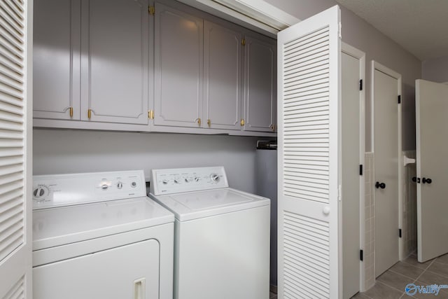 laundry area with light tile patterned floors, washing machine and dryer, and cabinets