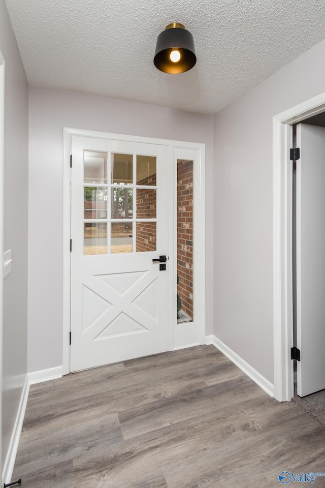 doorway with a textured ceiling and light wood-type flooring