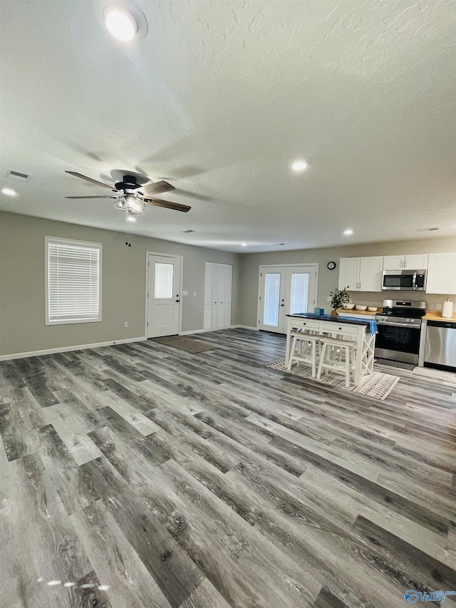 living room with wood-type flooring, french doors, a textured ceiling, and ceiling fan