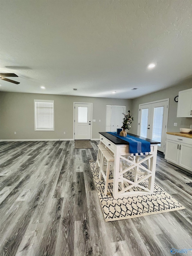 kitchen with french doors, white cabinets, light hardwood / wood-style flooring, ceiling fan, and a breakfast bar area