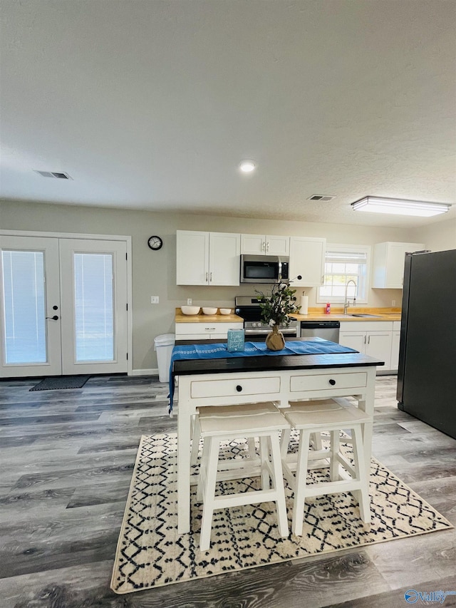 kitchen with white cabinets, hardwood / wood-style floors, stainless steel appliances, and sink