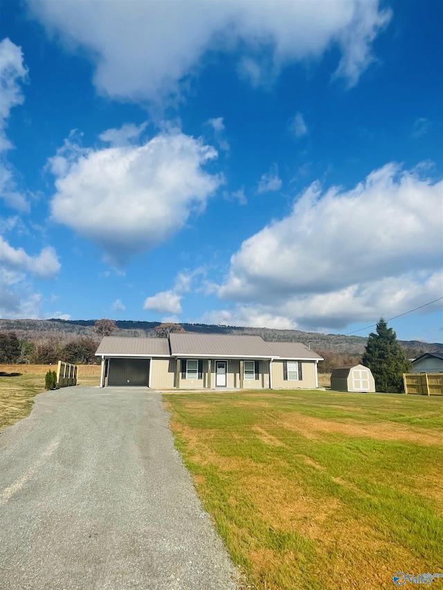 ranch-style home featuring a front lawn and a storage shed