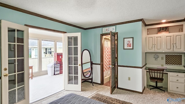 interior space featuring french doors, light colored carpet, built in desk, and a textured ceiling