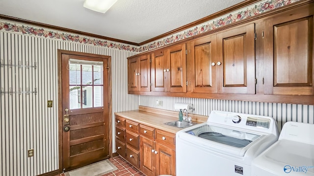 laundry room featuring sink, cabinets, independent washer and dryer, crown molding, and a textured ceiling