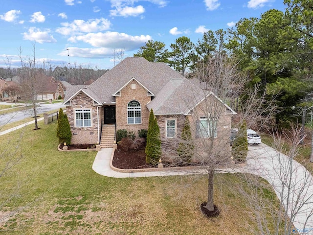 view of front of property featuring stone siding, a shingled roof, a front yard, and brick siding