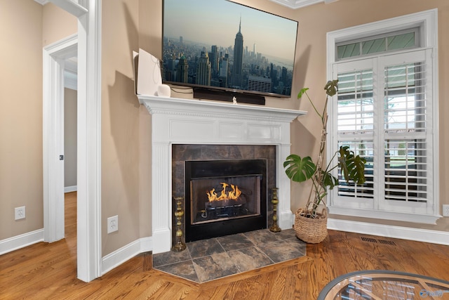 interior details featuring visible vents, a fireplace, baseboards, and wood finished floors