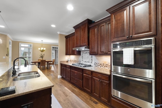 kitchen featuring stainless steel appliances, ornamental molding, a sink, and decorative backsplash